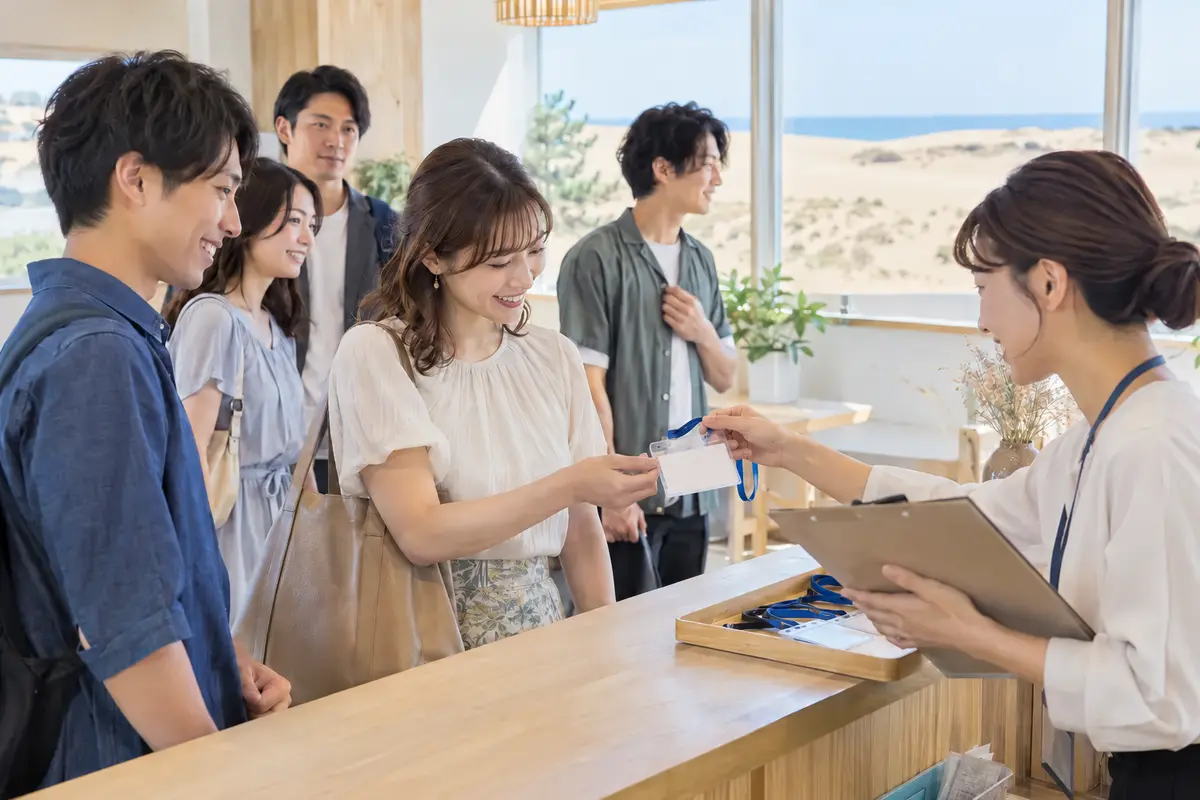 明るい受付でスタッフが参加者を自然な笑顔で迎える様子